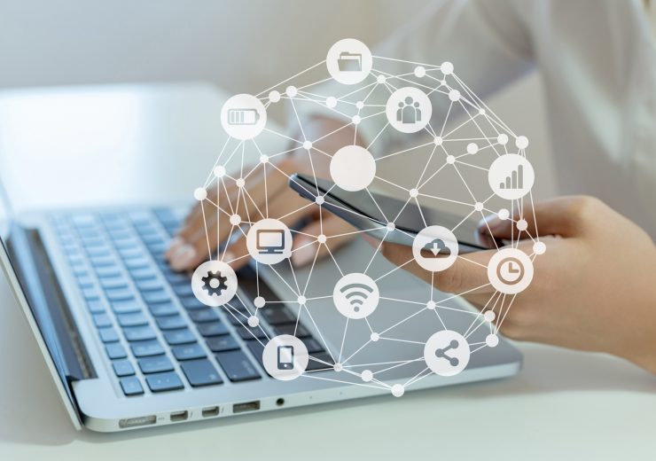 Woman holding mobile phone and using laptop