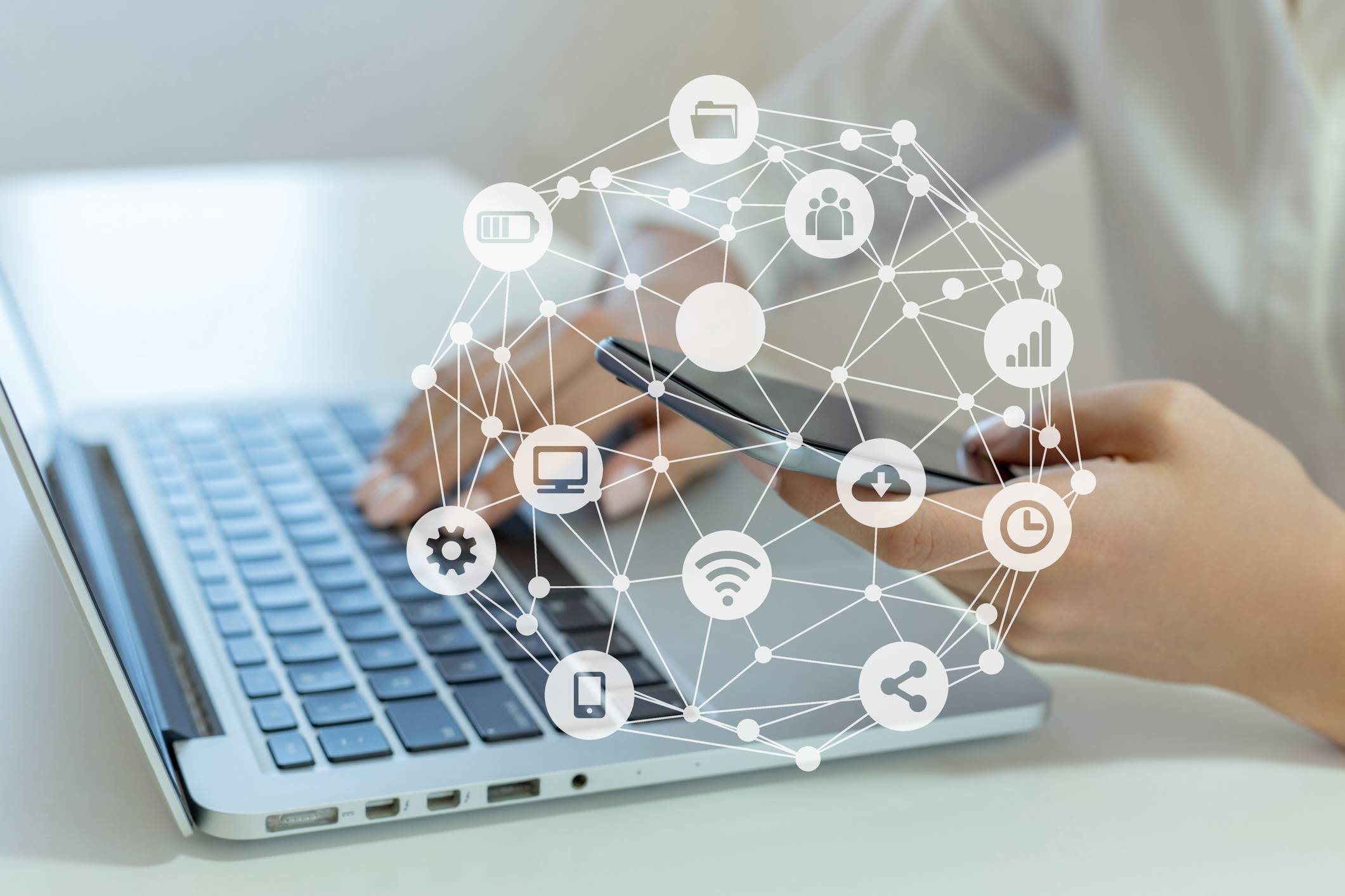 Woman holding mobile phone and using laptop